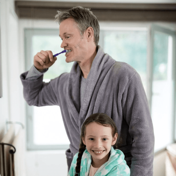 Father and daughter brushing their teeth