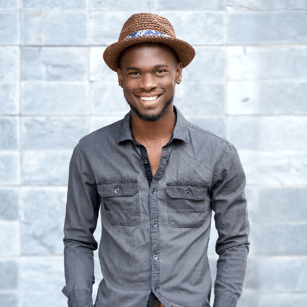 A Happy Young Man With a Hat Standing in Front of a Wall