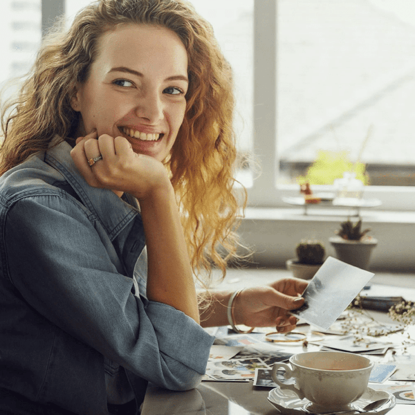 Lady Holding a Picture While Having a Cup of Coffee